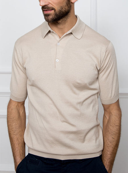 Man wearing almond beige short sleeved polo sweater knit in 100% luxury and premium merino wool.